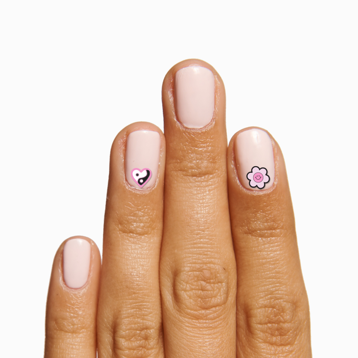 Hand with light pink polish featuring heart and flower nail stickers from Frasier Sterling Pack for playful mani designs