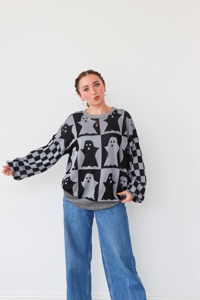 Woman wearing a patterned sweater and jeans against a white background