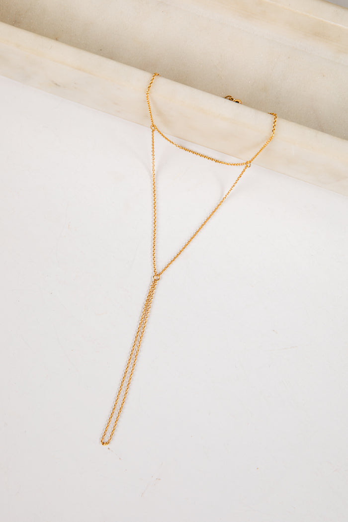 Gold necklace on a white surface with a light wood background