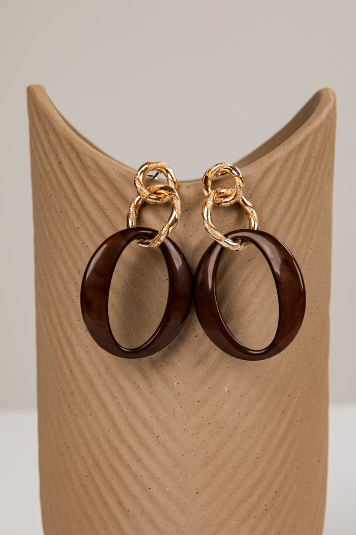 Wooden hoop earrings with gold loops on a wooden stand.