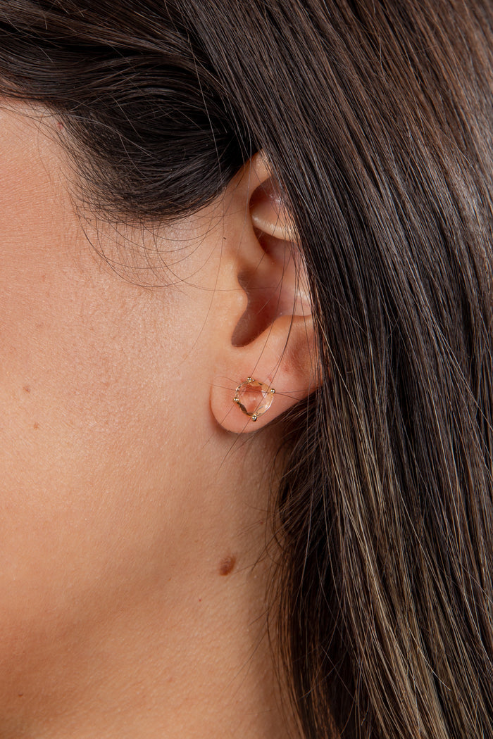 Close-up of an ear with a gold earring against a blurred background