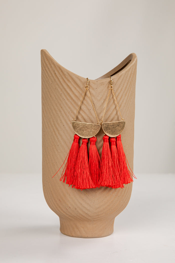 Beige decorative vase with red tassels on a light gray background
