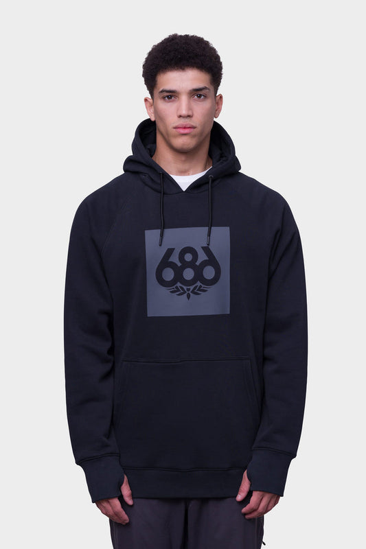A young man faces forward in a 686 Mens Knockout Pullover Hoody by 686, featuring a black color, large front pocket, and bold gray 686 logo on the chest. The background is plain white.