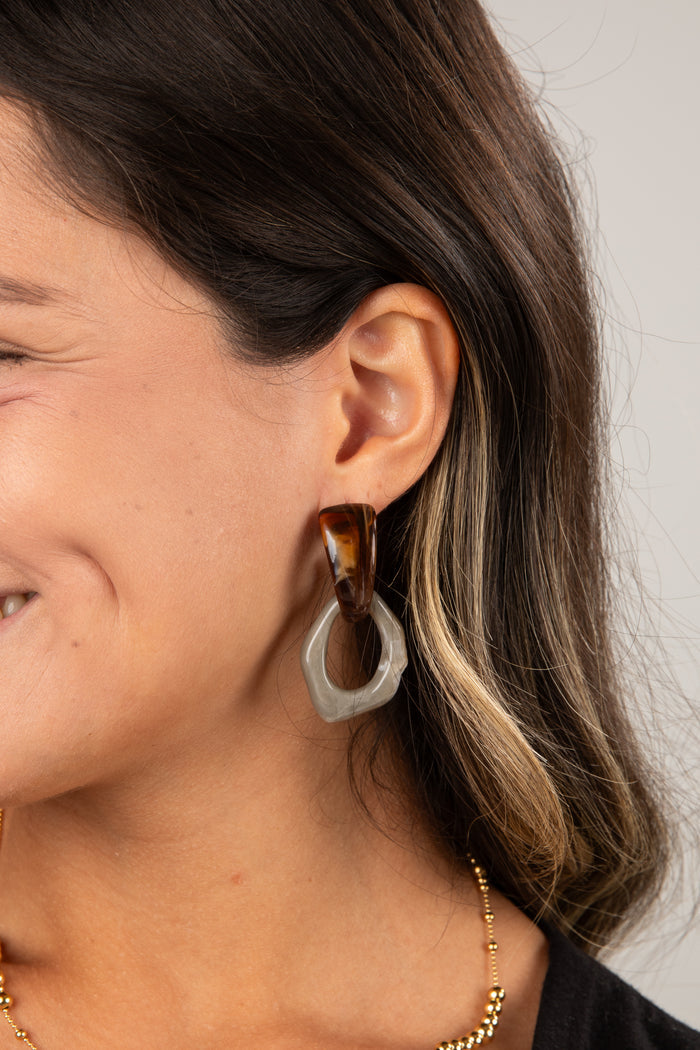 Close-up of a person wearing a tortoiseshell hoop earring with a white circular accent.