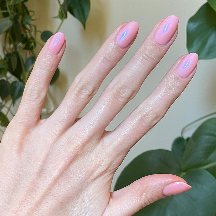 Hand with Candy Shoppe manicure showing smooth pink nails with subtle iridescent shimmer in natural light