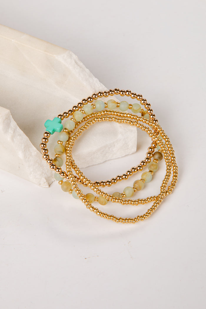 Set of gold and green beaded bracelets on a light background
