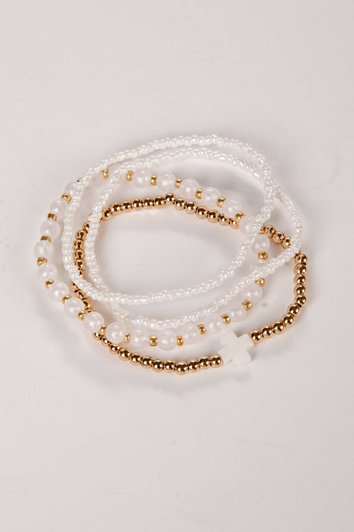 Set of pearl and gold beaded bracelets on a light background