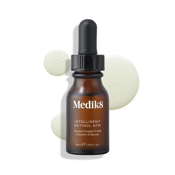Medik8 Intelligent Retinol 6TR serum bottle stands against a clean white background with three clear liquid droplets. Text identifies the product as a 15ml "Supercharged 0.6% Vitamin A Serum."