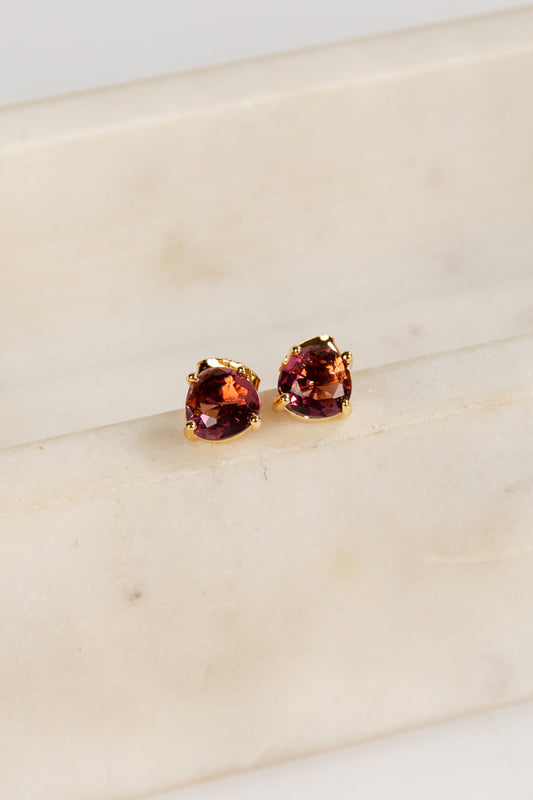 Pair of red gemstone stud earrings on a light beige surface