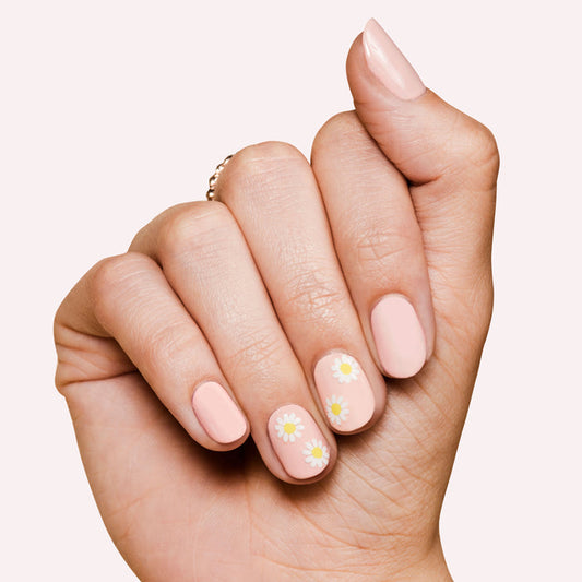 Hand showing pastel pink manicure with daisy nail art representing Loveliest Day press-on nails product