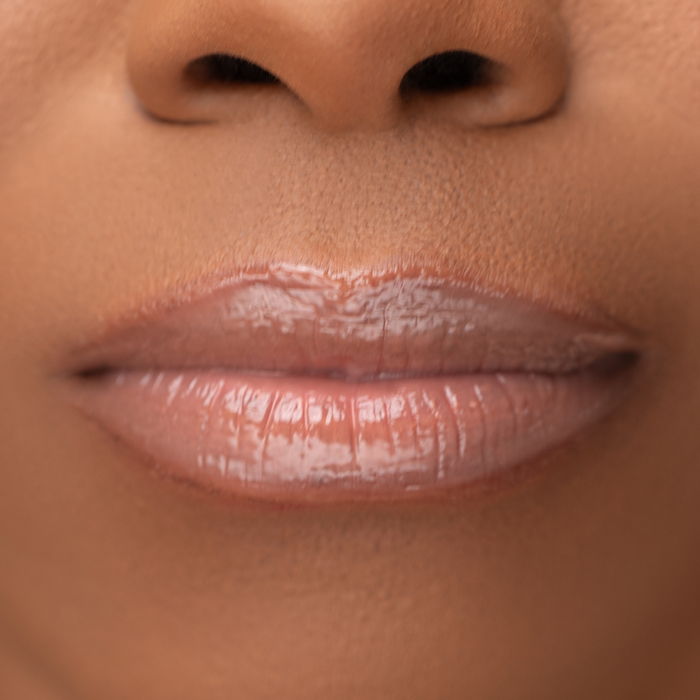 Close-up of LippEase Tinted Lip Treatments HER showing glossy nude high shine finish on medium skin tone. Neutral Brown Liner Lip Combos
