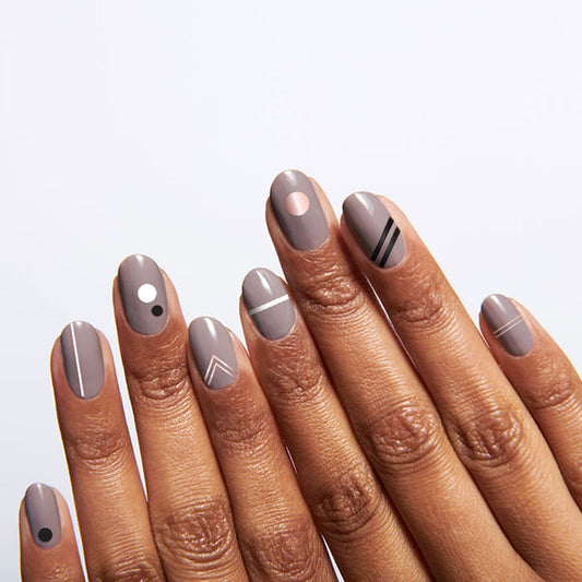 Hand with nails featuring On the Dotted Line geometric mani in taupe with white, black, and rose gold accents