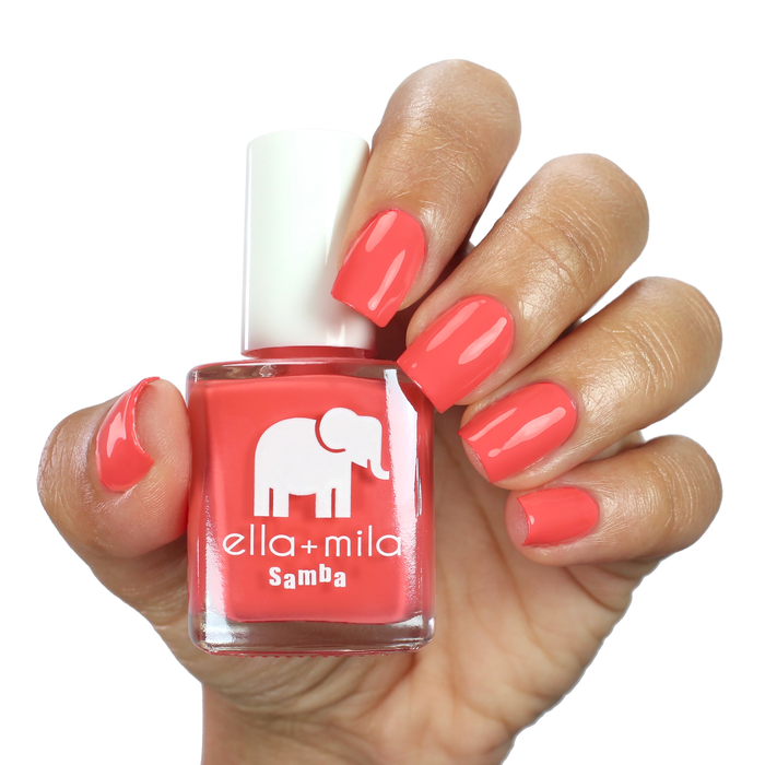 One in a Melon red orange nail polish on a medium skin tone, hand holding the bottle
