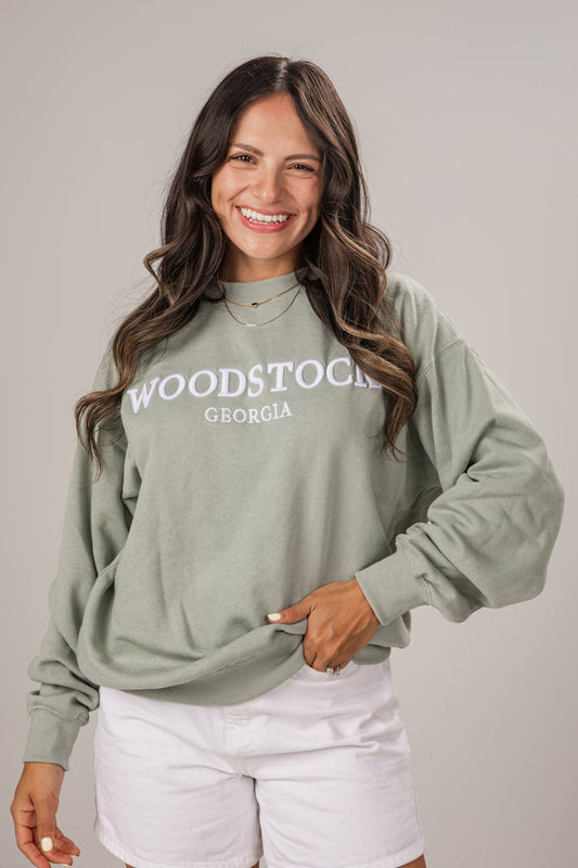 Woman wearing a green sweatshirt with 'Woodstock, Georgia' text on a plain background